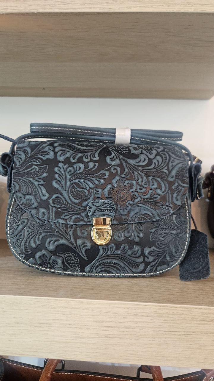 Un bolso pequeño cuero en forma de media luna destaca por su silueta curva y su estética contemporánea.