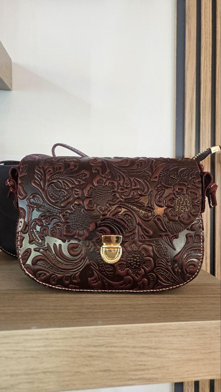 Un bolso pequeño cuero en forma de media luna destaca por su silueta curva y su estética contemporánea.